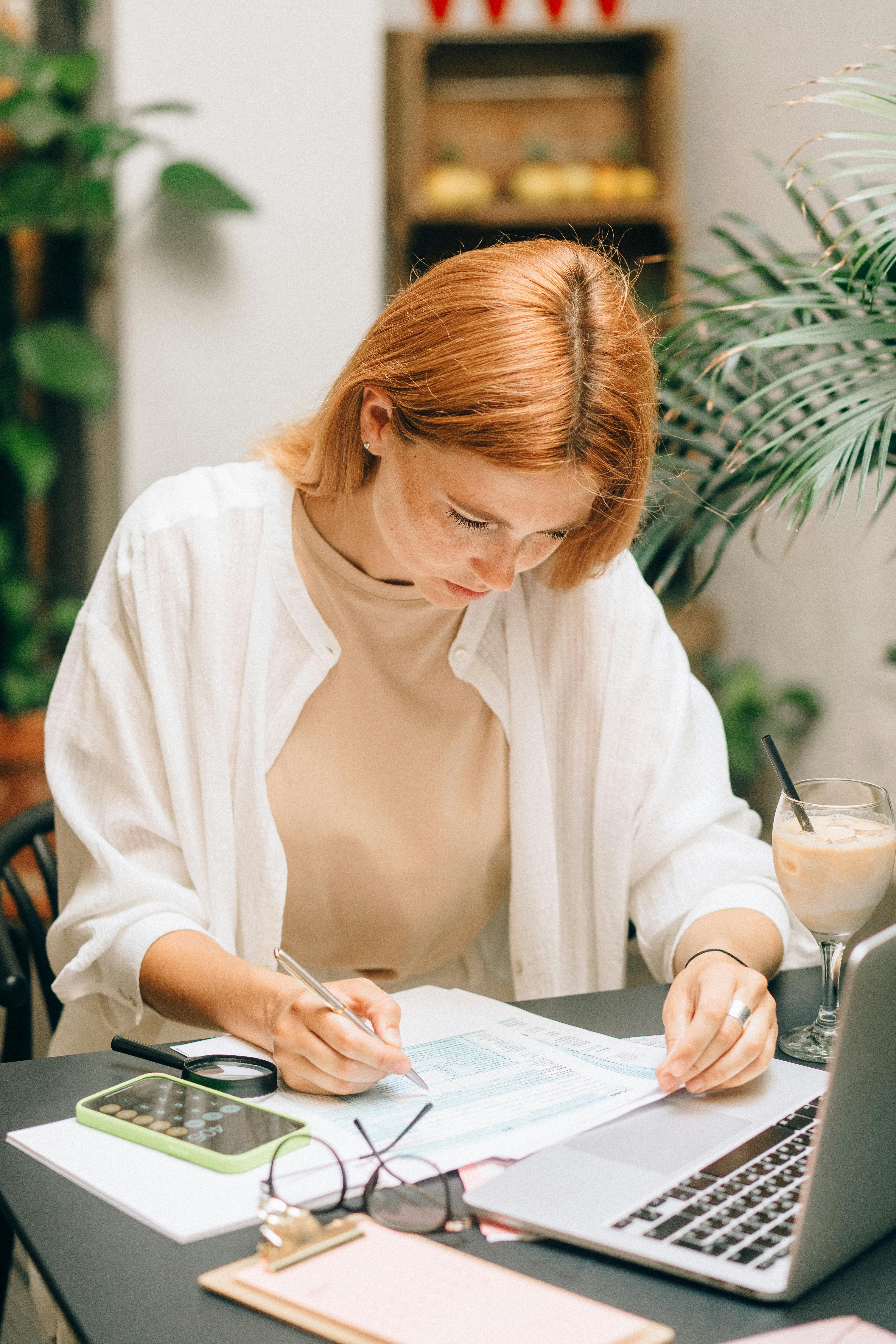 Woman sitting at a desk writing in a notebook while planning her childcare business